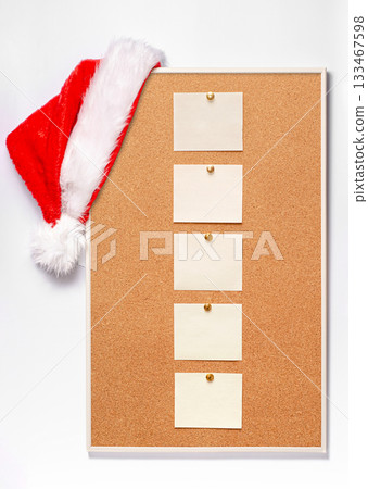 Blank note sheets are pinned to the board. Santa's hat on a cork board. Blank note sheets are pinned to the board. Santa's hat on a cork board. 133467598