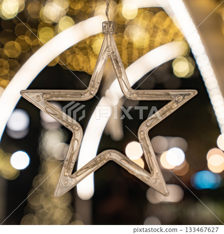 A star shaped clear light appears against warm golden bokeh, and the glowing circles form a gentle festive mood. 133467627