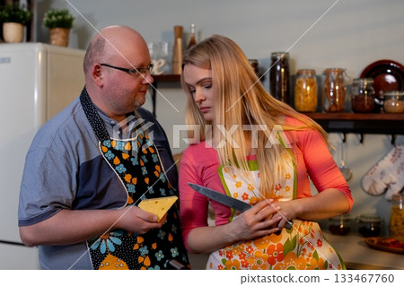 Father guides daughter in cooking, Parent instructs child during kitchen meal prep, Family members collaborating in kitchen to follow recipe and prepare meals together 133467760