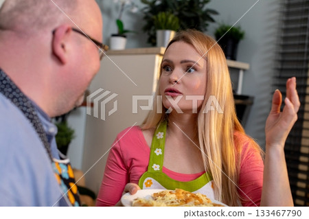 Familiar family members engage in passionate kitchen conversation about recipes, Tense yet intimate discussion between relatives over recipe modifications in cozy kitchen 133467790