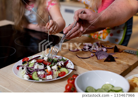 Colorful cooking scene, Young helper watches as ingredients are carefully assembled, Vivid kitchen atmosphere with child observing and participating in salad preparation Colorful cooking scene, Young helper watches as ingredients are carefully assembled, Vivid kitchen atmosphere with child observing and participating in salad preparation 133467966