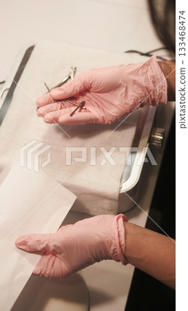 Professional manicure. Nail hygiene. Female master hands taking tools forceps preparing for steam sterilization instruments from bacterial viral infections. 133468474