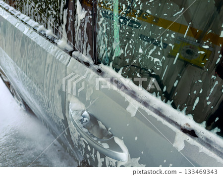 Foamy car wash experience on a sunny afternoon in the neighborhood, creating a refreshing atmosphere and clean vehicles 133469343