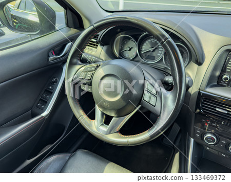 Interior view of a car's steering wheel showing controls and dashboard details captured during a sunny day Interior view of a car's steering wheel showing controls and dashboard details captured during a sunny day 133469372