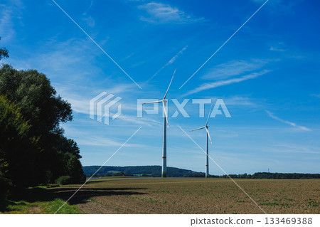 Wind turbines stand tall against a clear blue sky in a rural landscape during a sunny day Wind turbines stand tall against a clear blue sky in a rural landscape during a sunny day 133469388