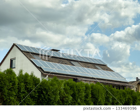 Solar panels shine brightly on a modern house under a cloud-filled sky, showcasing renewable energy solutions in a peaceful neighborhood 133469396