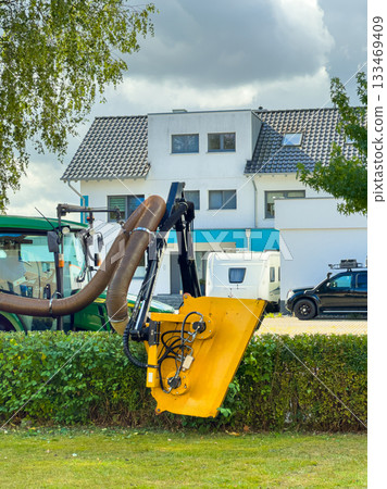 Innovative machinery trims greenery along a suburban street in bright daylight with clouds in the sky 133469409