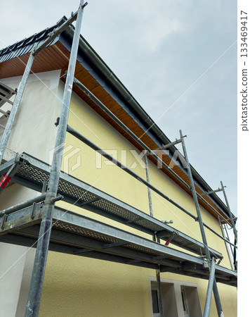Construction workers skillfully applying fresh paint to a building under clear skies in a suburban neighborhood Construction workers skillfully applying fresh paint to a building under clear skies in a suburban neighborhood 133469417