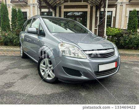 Silver minivan parked elegantly outside a beautiful brick building on a cloudy day, showcasing modern design and stylish features Silver minivan parked elegantly outside a beautiful brick building on a cloudy day, showcasing modern design and stylish features 133469422