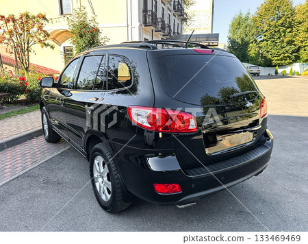 Black SUV parked outside a beautiful mansion on a sunny day, showcasing modern design and elegance in a serene environment Black SUV parked outside a beautiful mansion on a sunny day, showcasing modern design and elegance in a serene environment 133469469