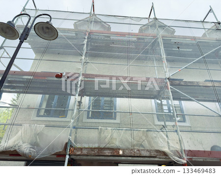 Scaffolding surrounds a historic building undergoing restoration during a cloudy afternoon in a bustling city 133469483