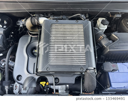 Detailed view of a modern car engine highlighting the complex components and engineering marvels found under the hood during a sunny afternoon Detailed view of a modern car engine highlighting the complex components and engineering marvels found under the hood during a sunny afternoon 133469491