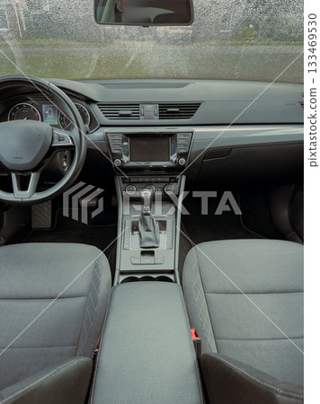 Interior view of a modern car showcasing a sleek dashboard and comfortable seating on a rainy day in a suburban area Interior view of a modern car showcasing a sleek dashboard and comfortable seating on a rainy day in a suburban area 133469530