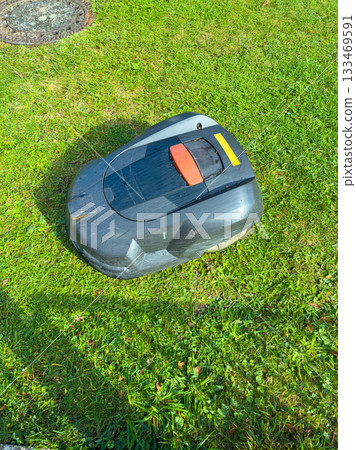 Robotic lawn mower navigates a vibrant green lawn during a sunny afternoon in a suburban garden Robotic lawn mower navigates a vibrant green lawn during a sunny afternoon in a suburban garden 133469591