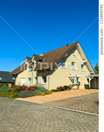 Bright sunny day highlights charming house with colorful garden and clear blue sky in a calm suburban neighborhood 133469595
