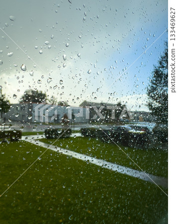 Raindrops decorate the window as nature awakens in a tranquil neighborhood during a moody afternoon 133469627