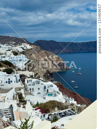 Discovering the stunning coastal beauty of Santorini as picturesque white buildings meet the azure waters under a cloudy sky 133469637