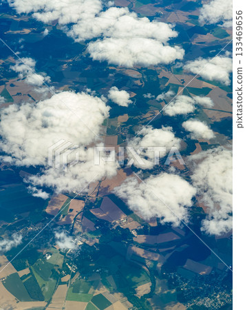 Scenic view of lush farmland and clouds taken from a high altitude during a daytime flight in a clear blue sky 133469656