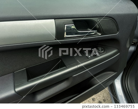 Details of a modern car door interior featuring sleek design, control buttons, and fabric texture captured in an urban setting on a cloudy day Details of a modern car door interior featuring sleek design, control buttons, and fabric texture captured in an urban setting on a cloudy day 133469755