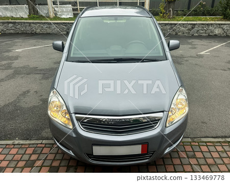Silver hatchback parked in a quiet lot surrounded by greenery and stone walls on a calm day Silver hatchback parked in a quiet lot surrounded by greenery and stone walls on a calm day 133469778