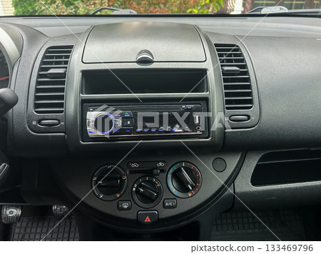 Modern dashboard of a vehicle showcasing its audio system and climate controls in a detailed close-up view 133469796