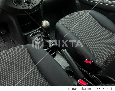 Interior view of a modern vehicle showcasing a manual transmission gear shift and comfortable seats in a cozy setting 133469801