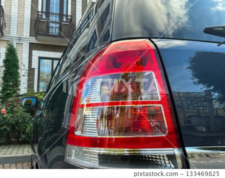Close-up view of a car tail light reflecting a beautiful garden on a sunny day in a quiet urban neighborhood 133469825