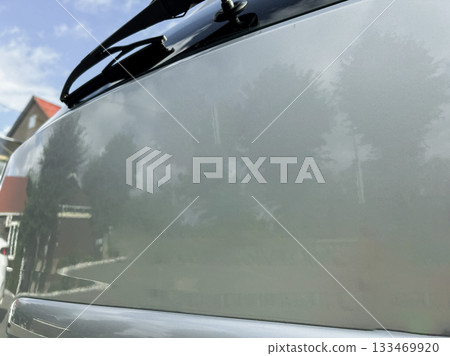 Reflective surface depicting a serene outdoor scene with trees and blue sky, captured during a bright, sunny afternoon in a peaceful neighborhood 133469920