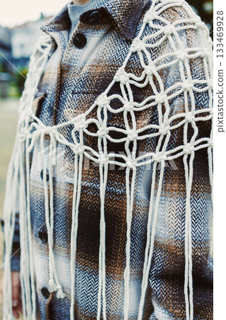 Unique textile art display featuring an intricately knotted design on a stylish flannel jacket in a serene outdoor setting during daylight hours 133469928