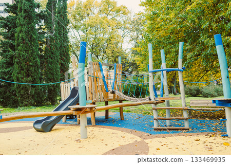 Children play and explore a colorful playground surrounded by lush trees on a bright autumn day Children play and explore a colorful playground surrounded by lush trees on a bright autumn day 133469935
