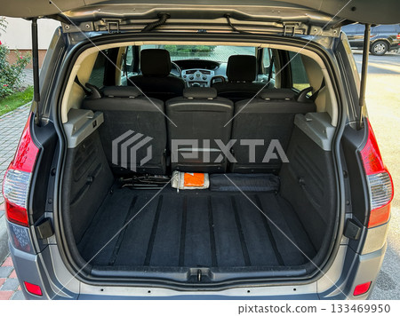 Open trunk shows spacious interior of a gray SUV parked, ready for adventures and cargo hauling on a sunny day 133469950