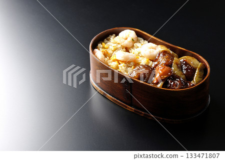 蝦仁炒飯和黑醋糖醋豬肉便當,以黑色背景拍攝。 蝦仁炒飯和黑醋糖醋豬肉便當,以黑色背景拍攝。 133471807
