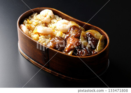 Shrimp fried rice and black vinegar sweet and sour pork bento photographed against a black background 133471808