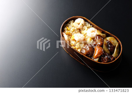 蝦仁炒飯和黑醋糖醋豬肉便當,以黑色背景拍攝。 蝦仁炒飯和黑醋糖醋豬肉便當,以黑色背景拍攝。 133471823