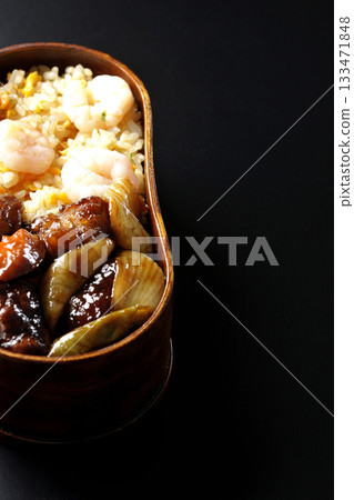 Shrimp fried rice and black vinegar sweet and sour pork bento photographed against a black background 133471848