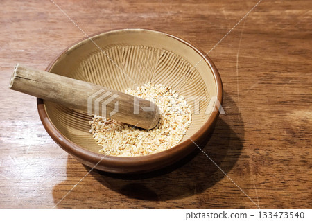 Grinding White Sesame Seeds in a Traditional Japanese Mortar. Grinding White Sesame Seeds in a Traditional Japanese Mortar. 133473540