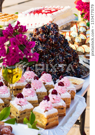 Tower of Chocolate Profiteroles with Assorted Desserts and Cupcakes.  133477079
