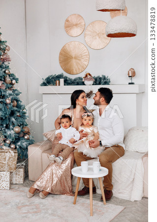 Family celebration in a cozy living room decorated for a festive occasion with a beautiful Christmas tree and warm ambiance 133478819