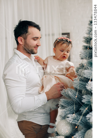 Father and daughter enjoy moments together decorating a Christmas tree in a cozy room filled with holiday spirit and joy 133478844