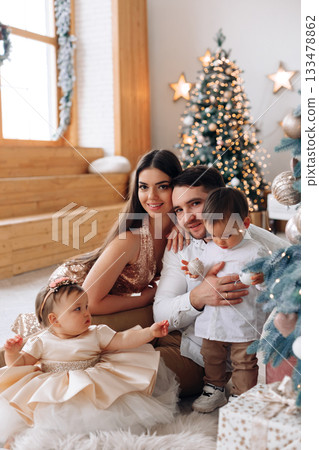 Family enjoying a festive moment together during Christmas with decorated tree and warm holiday spirit in a cozy living room Family enjoying a festive moment together during Christmas with decorated tree and warm holiday spirit in a cozy living room 133478862
