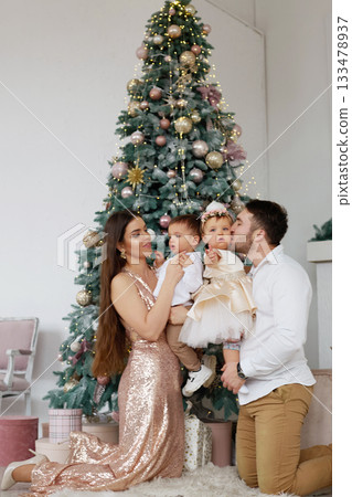 Family celebration in elegant attire near a beautifully decorated Christmas tree during the festive season Family celebration in elegant attire near a beautifully decorated Christmas tree during the festive season 133478937