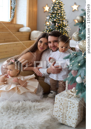 Family celebration with children during festive season in a cozy living room filled with decorations Family celebration with children during festive season in a cozy living room filled with decorations 133478949
