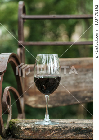 Glass of Red Wine on Wooden Bench in Summer Park 133479162