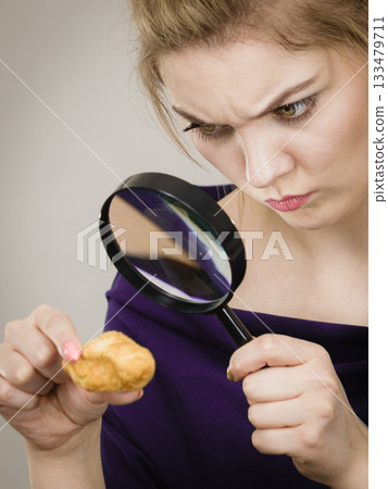 Woman holding magnifying glass investigating bread 133479711