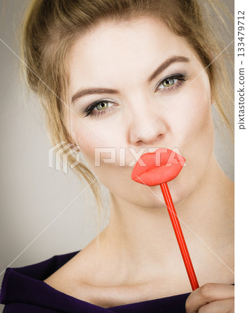 Funny woman holding big red lips on stick Funny woman holding big red lips on stick 133479712