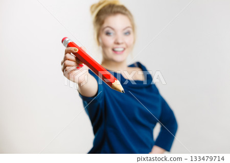 Happy woman holding giving big pencil Happy woman holding giving big pencil 133479714