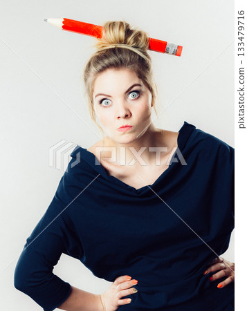 Confused blonde woman having big pencil in hair Confused blonde woman having big pencil in hair 133479716
