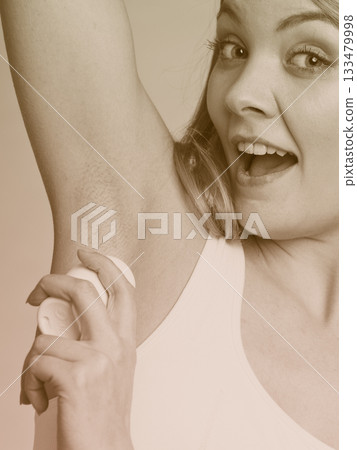 Girl applying stick deodorant in armpit. 133479998