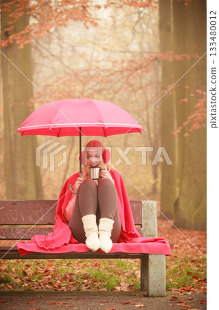 Girl sitting in park with umbrella 133480012