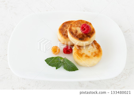 Curd fritters with raspberries on the white plate. Curd fritters with raspberries on the white plate. 133480021